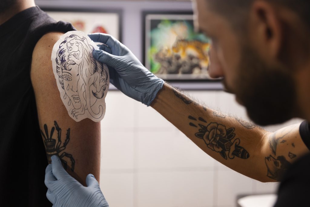 A tatuagem é planejamento, técnica e arte; cada traço começa no decalque, etapa essencial para garantir simetria, proporção e precisão no desenho final / Foto: Freepik